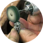 A jeweler is using a rotary tool to polish a ring