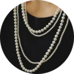 A woman wearing a white pearl necklace with three strands